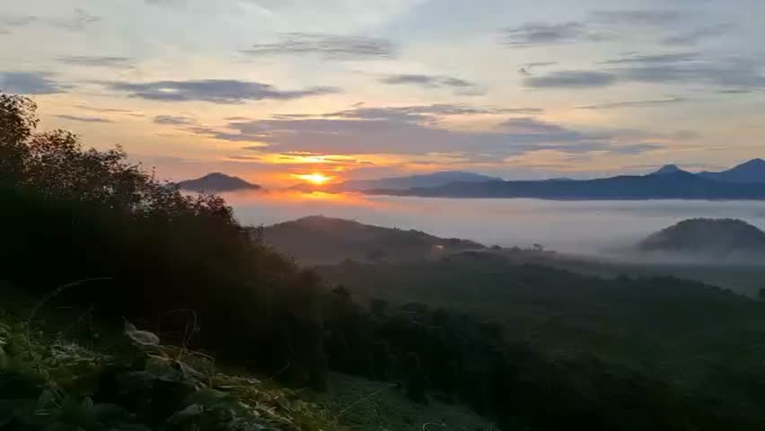 Golden sunrise above foggy hills and distant mountains