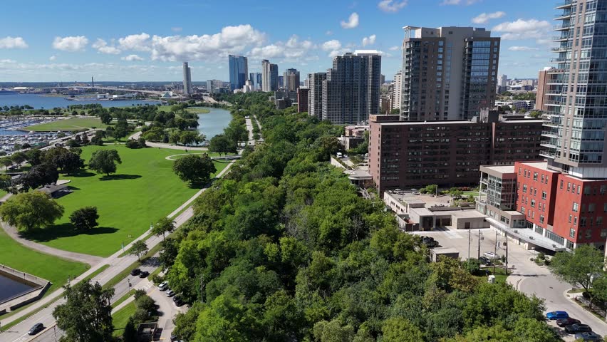 Aerial of Downtown Milwaukee Wisconsin on Labor Day Weekend.  Drone push show of lake drive and east side of town.  High Rise buildings and clouds dot the blue sky.
