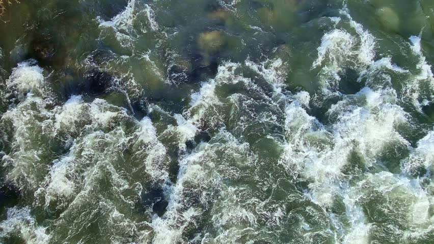 Top view of mountain river rapids with blue water and rock boulders, 4K