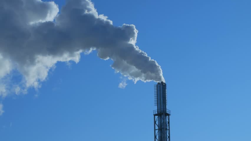 Smoke coming out of a factory chimney against a blue sky. Steam coming out of a chimney. Contrast. Nature and man.