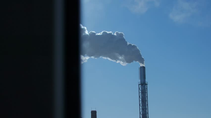 Smoke coming out of two tall factory chimneys against a blue sky. Steam coming out of two chimneys. Air pollution. Contrast.