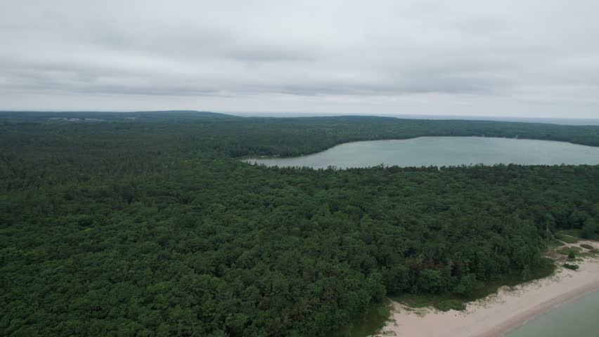 Push Drone shot of Europe Lake and Lake Michigan in Northern Door County Wisconsin on summer overcast day.  Tree lined Calm Water.