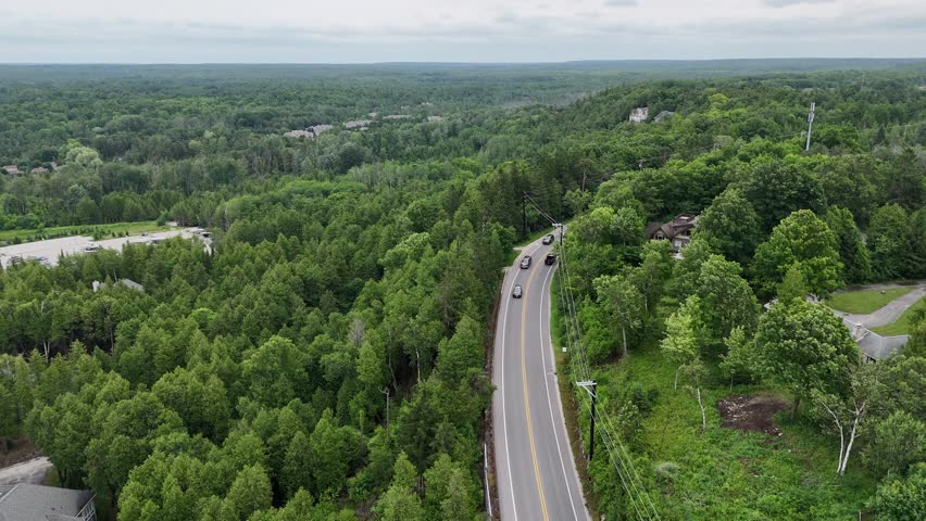 Aerial of Fish Creek in Door County Wisconsin on an overcast day.  Drone push shot over road with cars and hilly terrain in the distance.