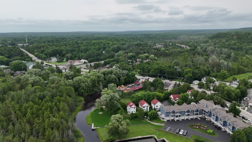 Aerial of Fish Creek in Door County Wisconsin on an overcast day.  Drone push shot over town and into wooded area.  Cloudy Horizon in the distance.