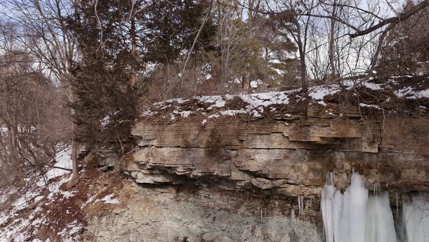 Left to Right drone shot of ice near frozen waterfall on bedrock cliff in Green Bay Wisconsin.