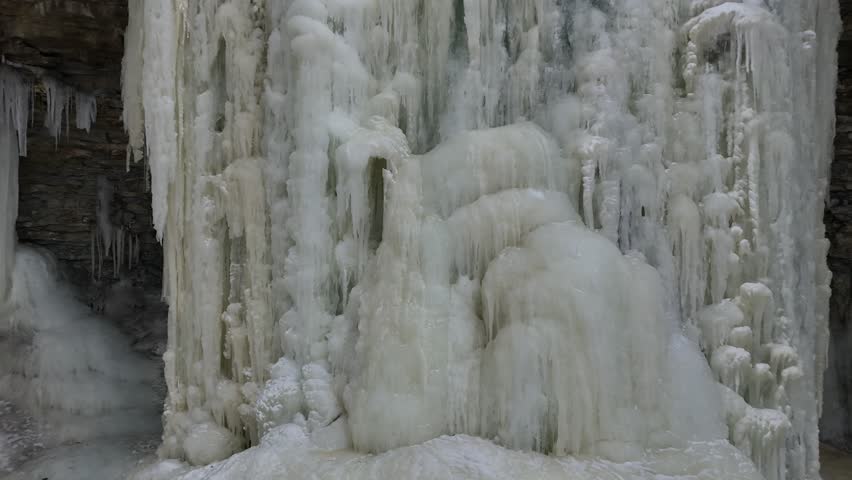 Aerial long pull shot of Frozen Waterfall in Green Bay Wisconsin.  Revealing River and snow below, starting very close to Ice.