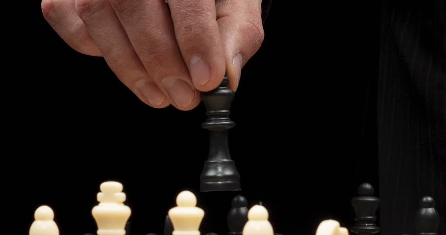 A zoom out of a businessman holding the black king chess piece doing a movement into a chess game in a geopolitical concept