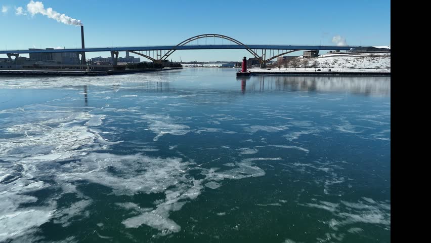 Winter Aerial in Milwaukee Wisconsin on the frozen shore of Lake Michigan.  Low approach to the Hoan Bridge over frozen river.