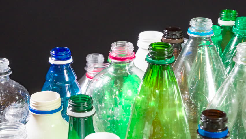 Assorted Plastic Bottles for Recycling. A close-up of colorful plastic bottles of various shapes and sizes moving slowly in a chaotic arrangement against a dark background. Ideal for themes of recycling, sustainability, or industrial processes