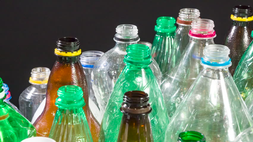 Assorted Plastic Bottles for Recycling. A close-up of colorful plastic bottles of various shapes and sizes moving slowly in a chaotic arrangement against a dark background. Ideal for themes of recycling, sustainability, or industrial processes