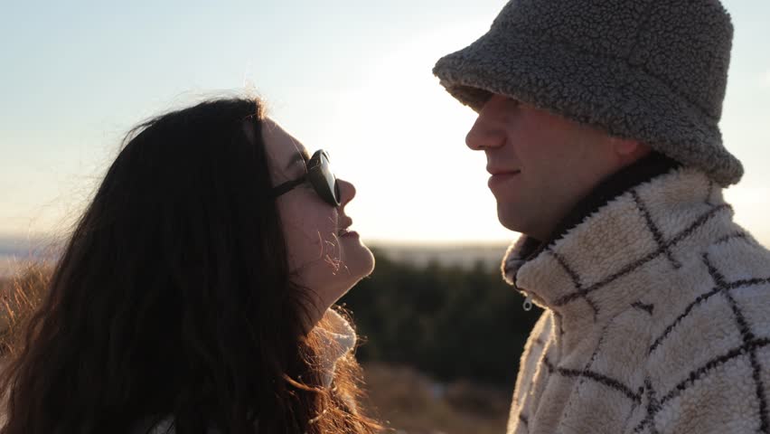 Happy young couple looking at each other silhouette in winter park at sunset light closeup. Romantic man and woman radiate affection and love at snowy countryside. Valentine day