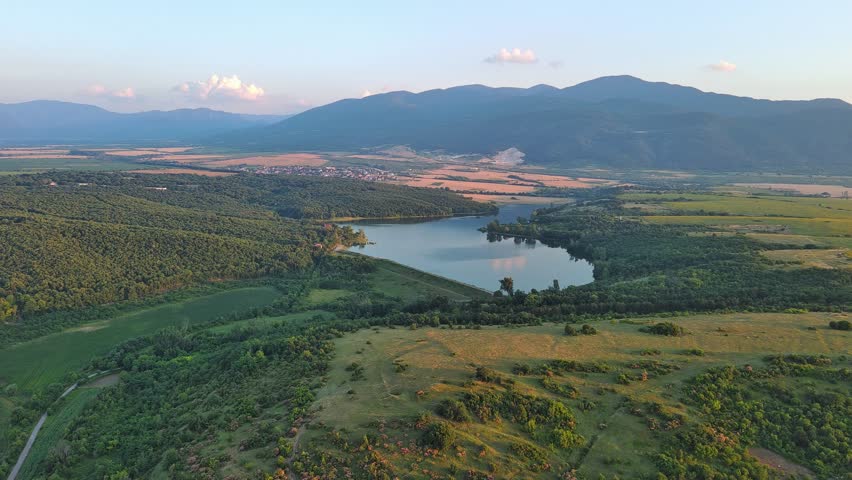 Mountain valley sheltered by vegetation and spruce forests with village of Smolyan with meadows where sheep graze