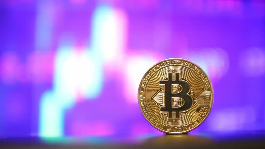 A close-up view of a Bitcoin coin placed in front of a vibrant financial chart background, showcasing the cryptocurrency market