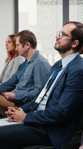 Vertical Video Male CEO attending conference and paying attention to discussion, international business forum and summit with stage presentation. Diverse participants in the conference hall. Camera A.