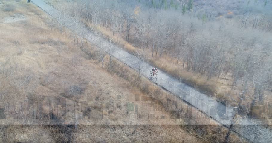 Drone panning and revealing mapping ID tags person icons timestamp while male teen riding trail. Cyclist, aerial, paved, rural, autumn, grassland, deciduous