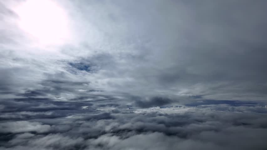Cockpit View from a jet cockpit while flying through multilayered stratus clouds, with a faded white sun veiled above.