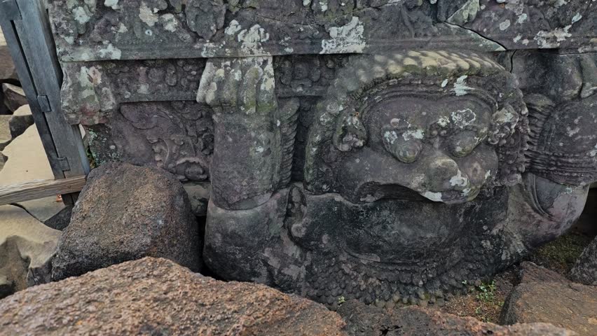 Pan right across weathered stone statues and carvings atop Koh Ker Pyramid Temple, Siem Reap