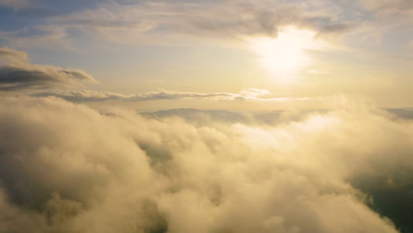 Sunset glowing beyond a thick cloud layer, creating a serene aerial view with warm light, soft clouds, and a peaceful, dreamy atmosphere.