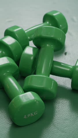 Vertical shot of light green dumbbells lying on floor in gym, no people around