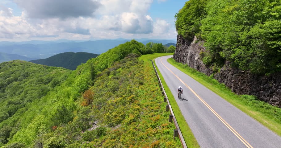 Cyclist riding a road bike along a scenic route in Appalachian Mountains, blending athletic performance, travel inspiration and outdoor exploration.