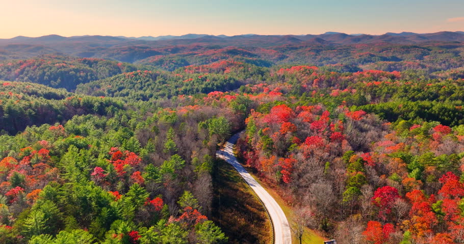 Scenic drive through Tennessee Appalachians at sunset in fall season. Car traveling on curvy forest road under vibrant autumn foliage.