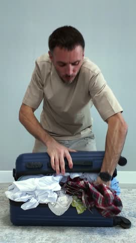 A tense traveler tries to close an overfilled suitcase