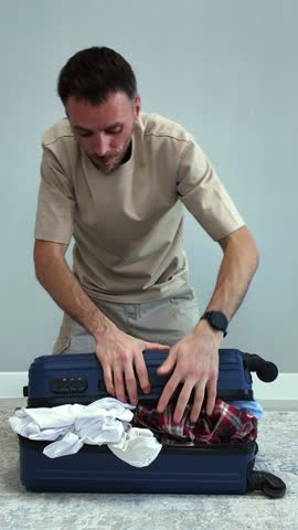 A tense traveler tries to close an overfilled suitcase