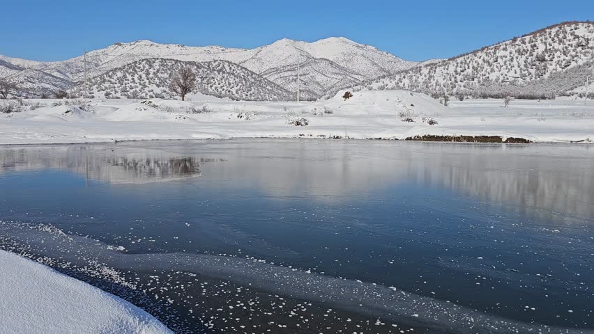 Serene winter landscape with a frozen river reflecting snow-covered mountains under a clear blue sky, evoking peaceful cold beauty.
📍Marivan, Kurdistan 