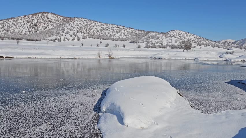 Serene winter landscape with a frozen river reflecting snow-covered mountains under a clear blue sky, evoking peaceful cold beauty.
📍Marivan, Kurdistan 