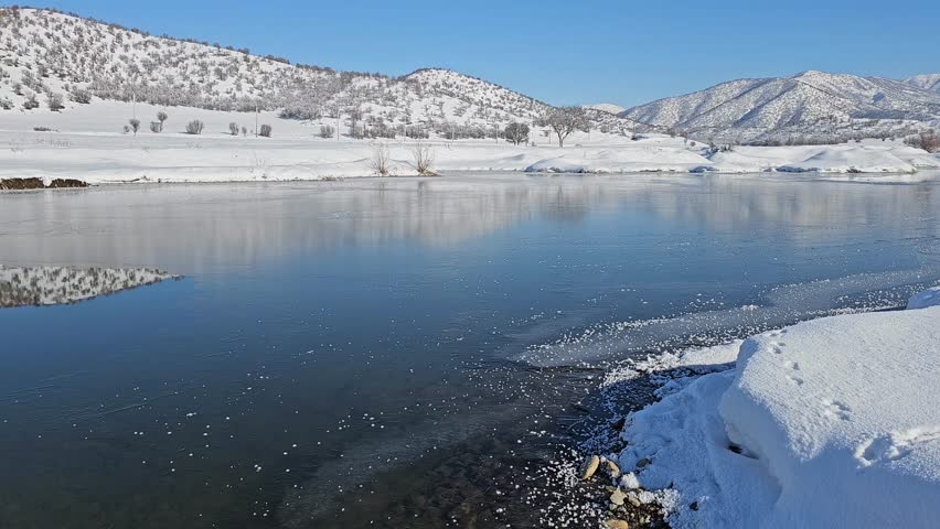 Serene winter landscape with a frozen river reflecting snow-covered mountains under a clear blue sky, evoking peaceful cold beauty.
📍Marivan, Kurdistan 