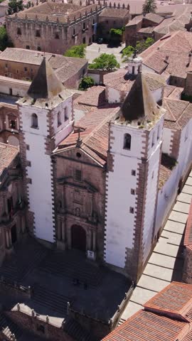 Vertical aerial view of Iglesia de San Francisco Javier in Cáceres, Spain, featuring its iconic bell towers and surrounding historic cityscape.