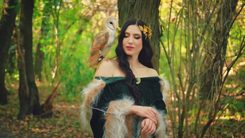 Art portrait Fantasy woman goddess elf, white tamed bird owl barn owl sits on shoulder. green yellow forest trees magical sun divine light. Green dress fur cape Greek style gold wreath. Summer nature.