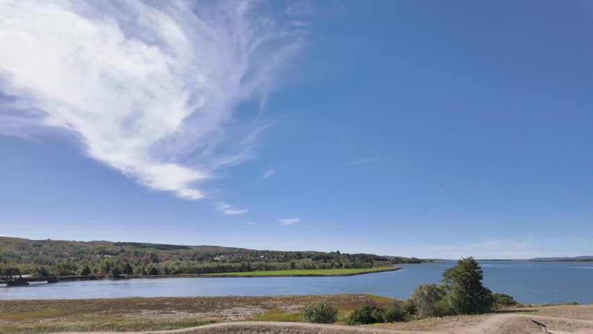 Slow motion footage of scenic view of the Annapolis Royal tidal river crossing in Nova Scotia Canada featuring a historic steel bridge calm waters forested hills and dramatic cloud formations 