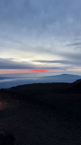 Vertical rotating view of Mauna Kea observatories and volcanic landscape at sunset