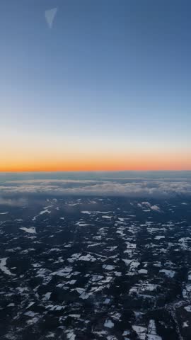 Vertical aerial view of sunrise above snowy Canadian landscape and cloud layer