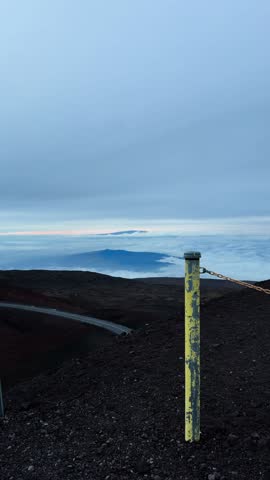 Vertical shot from Mauna Kea summit showing observatories above a sea of clouds under an overcast sky.