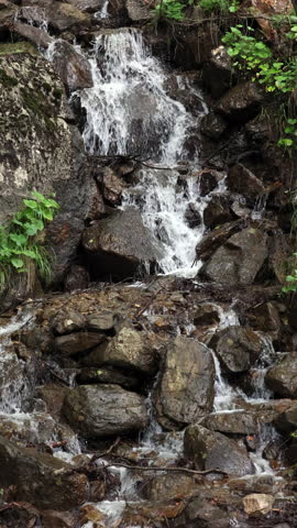 A Small Picturesque Waterfall Cascades Over Wet Rocks And Boulders. Nature
