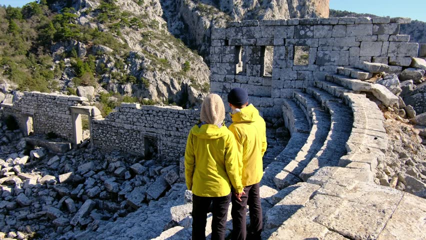 Young travelers discover ancient amphitheater and ruins of Termessos. Walking, climbing, enjoying view and ancient history in warm Turkish light.