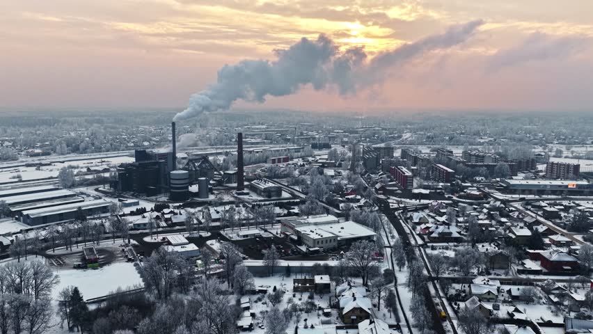 Winter cityscape with snow-covered buildings and industrial structures under soft seasonal light