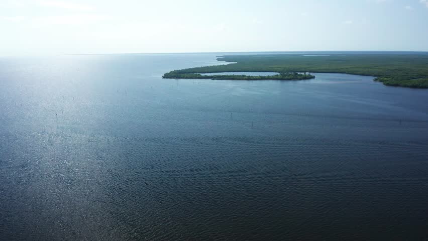 Open bay waters stretch toward low mangrove islands and shallow coastal wetlands in Florida Bay near Everglades National Park, conveying a calm, remote atmosphere shaped by wind and tide.