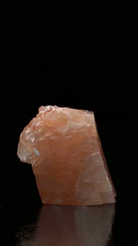 Orange Calcite crystal sample rotating slowly against a black background
