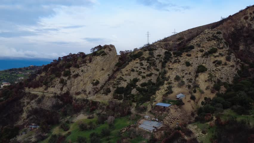Rocky fire damaged hillside with livestock herd and cloudy autumn sky