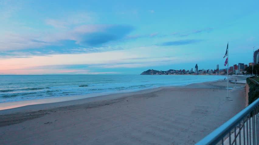 People walking on benidorm beach promenade at dawn