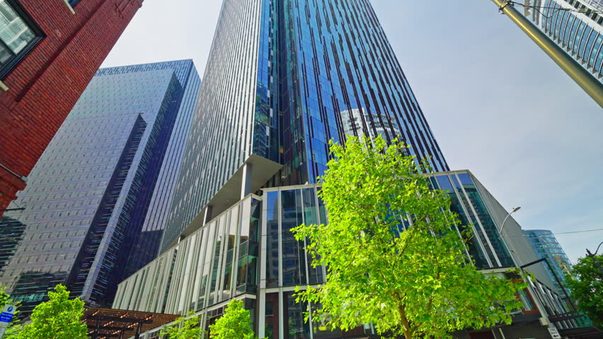 Panoramic view of Seattle’s glass skyscrapers under a clear blue sky. Sunlight reflects off modern towers, creating a bright downtown cityscape in Washington, USA.