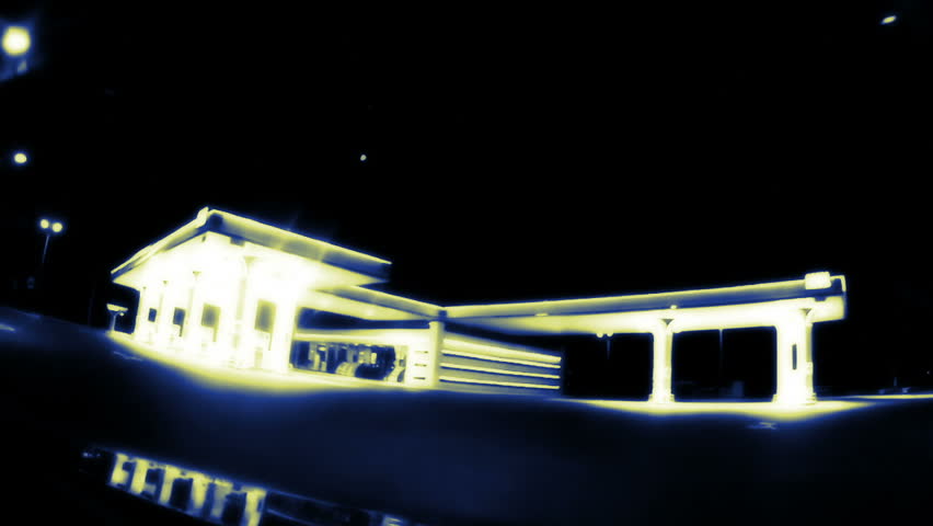 Dark night. The car drives through an empty gas station. Gas station illuminated