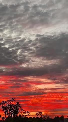 Dramatic cloudy sky during sunset with red and orange glowing clouds creating a natural atmospheric background.