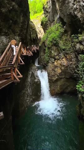 Wooden Walkway Above Waterfall in Mountain Gorge
