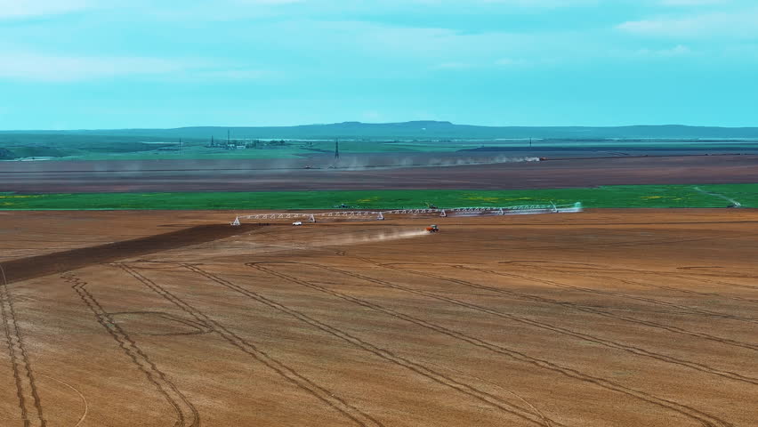Aerial footage of farmland with an operating center-pivot irrigation system. The panoramic view highlights the vast scale of the fields, modern irrigation methods, and the use of technology to improve crop yields and efficiently manage water resources. This video is ideal for agricultural presentations, educational projects, and content about modern farming.