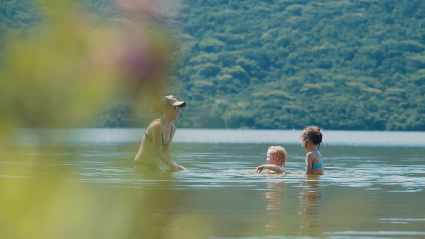 Family with kids has fun on the summer lake, enjoy the sunny weather and play with water
