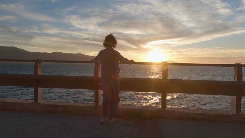 Tourist woman enjoy sunset panorama over the sea from a seaside promenade